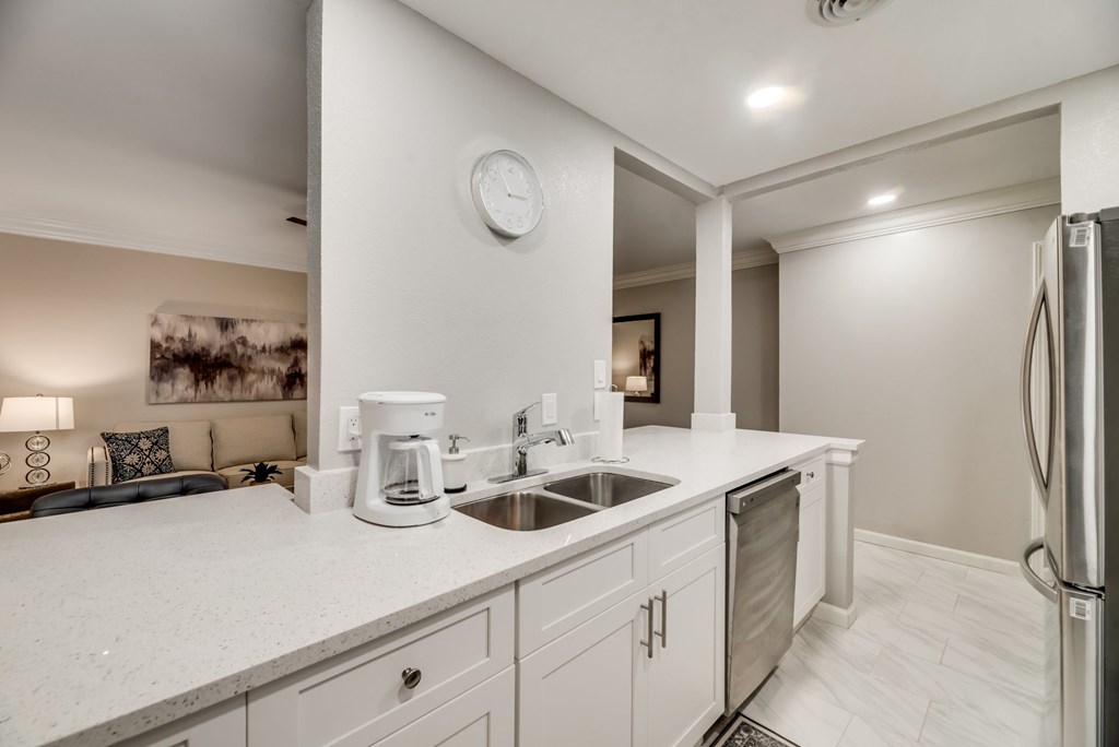 a kitchen with white counter tops and appliances and a living room with a couch