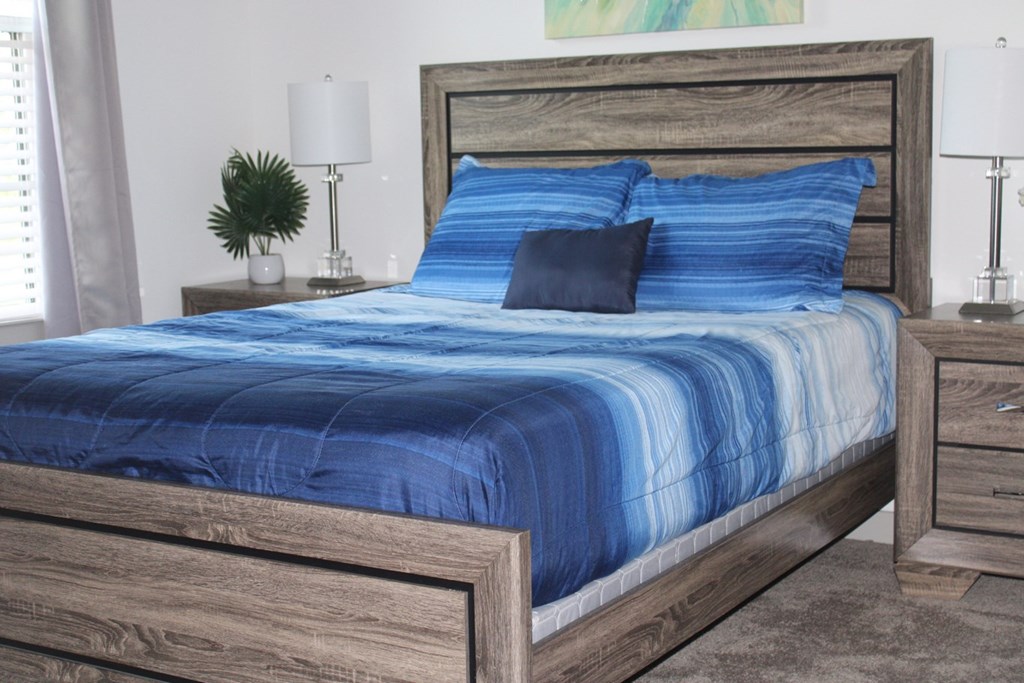 a bedroom with a bed with blue comforter and pillows