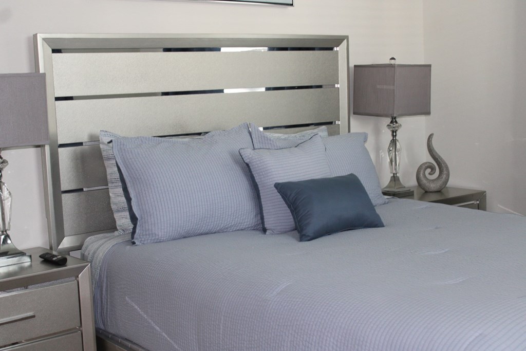 a white bed with blue pillows and a white headboard