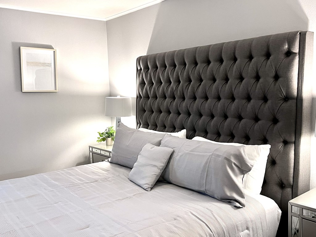 a bedroom with a large bed with pillows and a tufted headboard