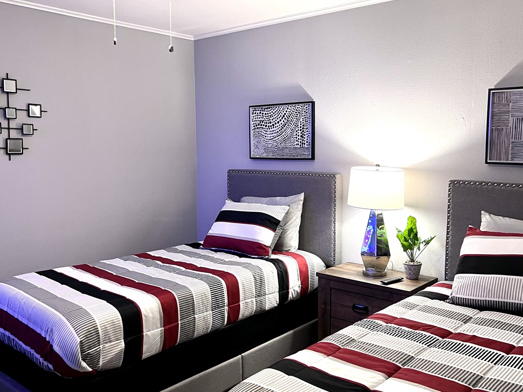 a guest room with two beds and a nightstand with a lamp