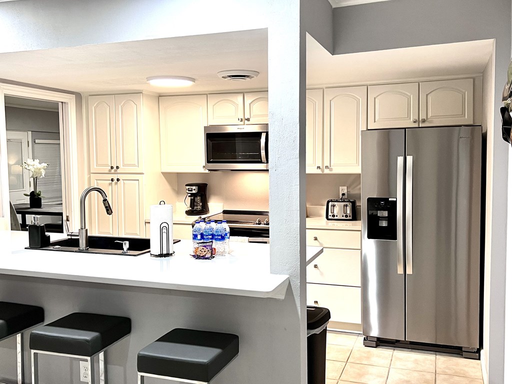 a kitchen with stainless steel refrigerator and a counter with stools
