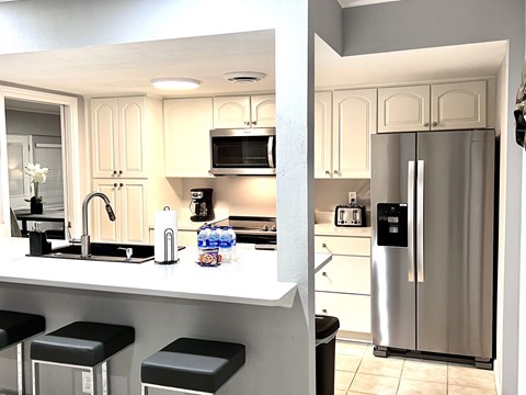 a kitchen with stainless steel refrigerator and a counter with stools