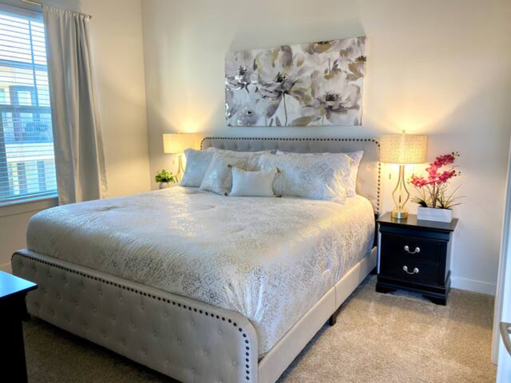 a bedroom with a bed and two lamps and a painting