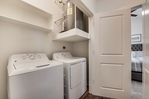 a washer and dryer in a laundry room with a door to a bedroom