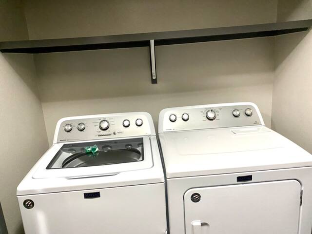 two white appliances in a room with a shelf above them