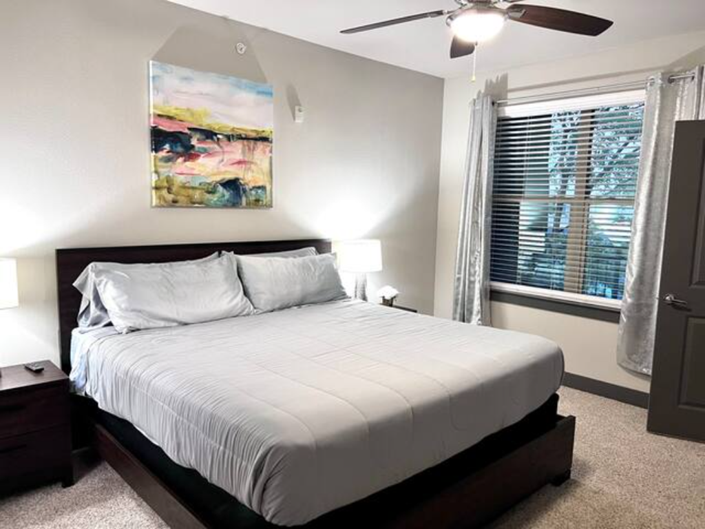 a bedroom with a white bed and a ceiling fan