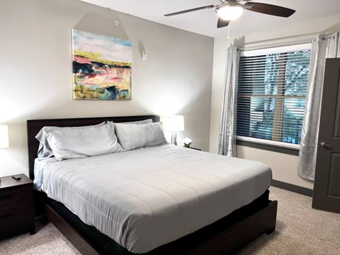 a bedroom with a white bed and a ceiling fan