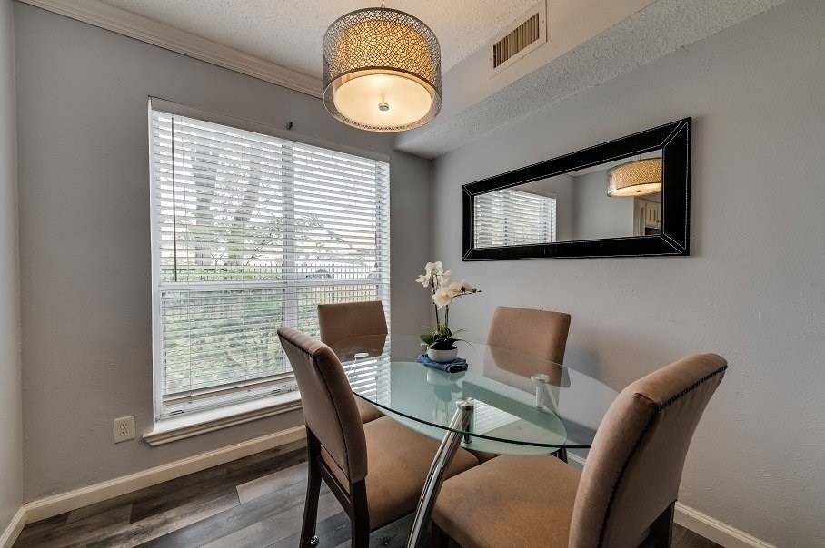 a dining room with a glass table and chairs and a large window