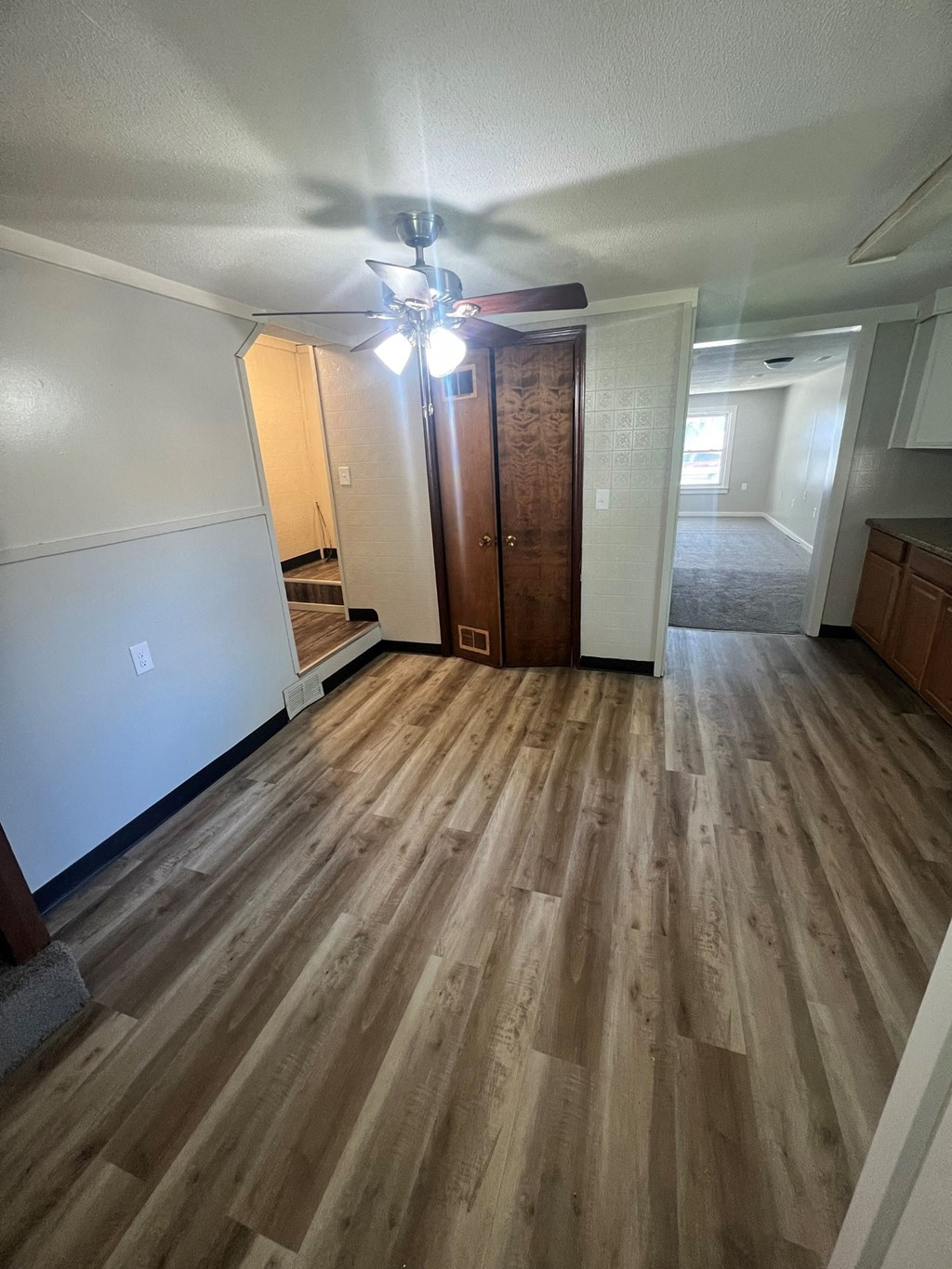 an empty living room with wooden floors and a ceiling fan
