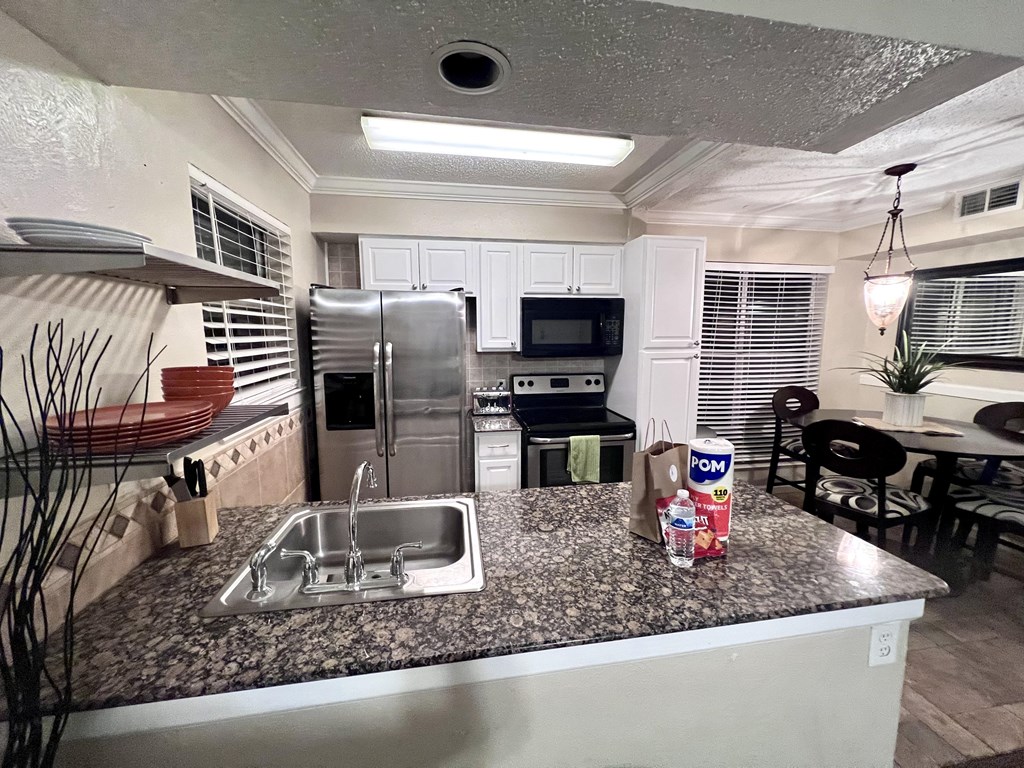 a kitchen with granite counter tops and a stainless steel refrigerator