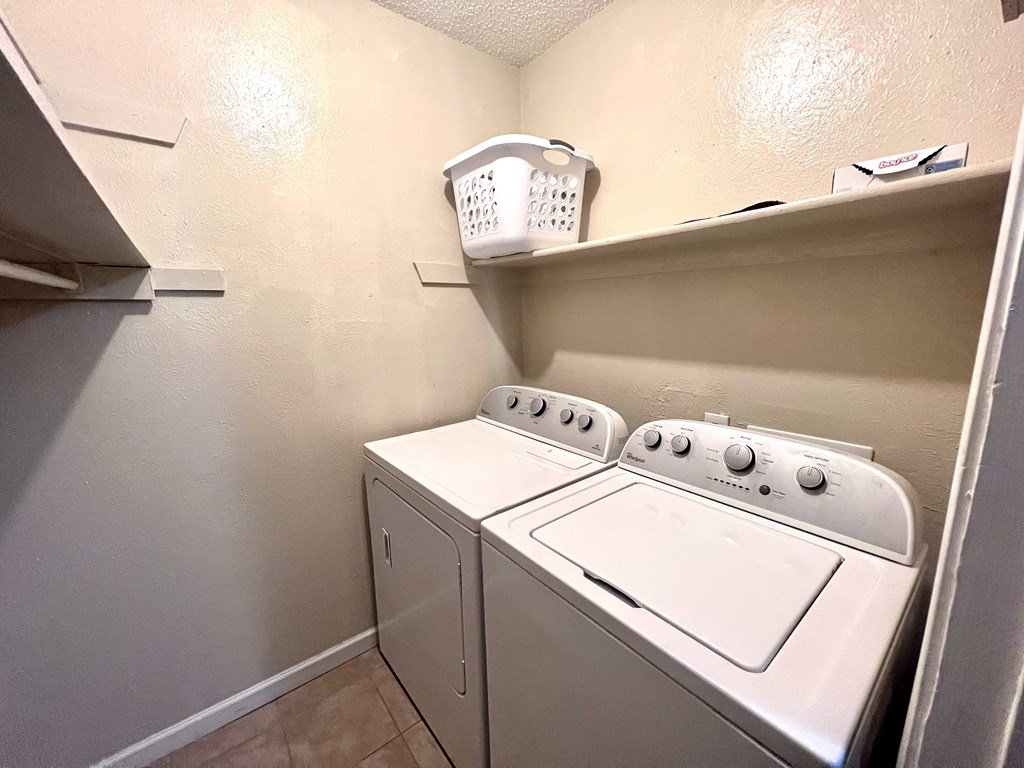 a white washer and dryer in a laundry room with a shelf above it