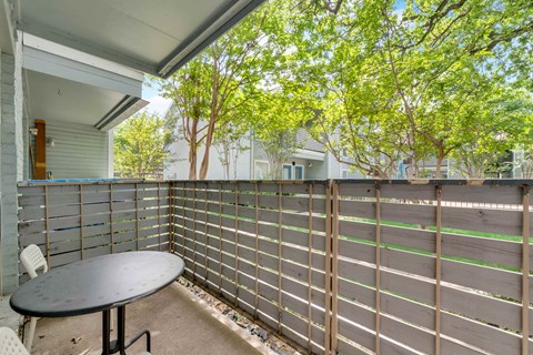 a patio with a table and a privacy fence