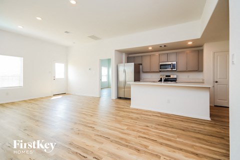 the living room and kitchen of an apartment with wood flooring