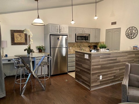 a kitchen with a stainless steel refrigerator and a bar with stools