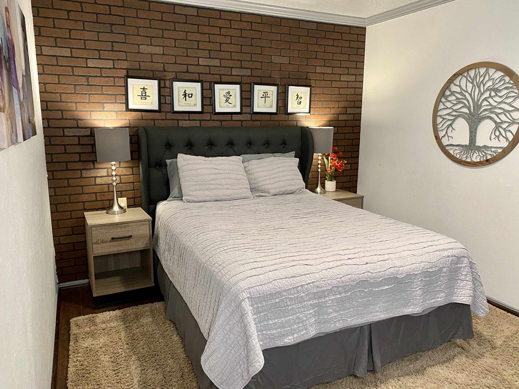 a bedroom with a bed and a brick wall