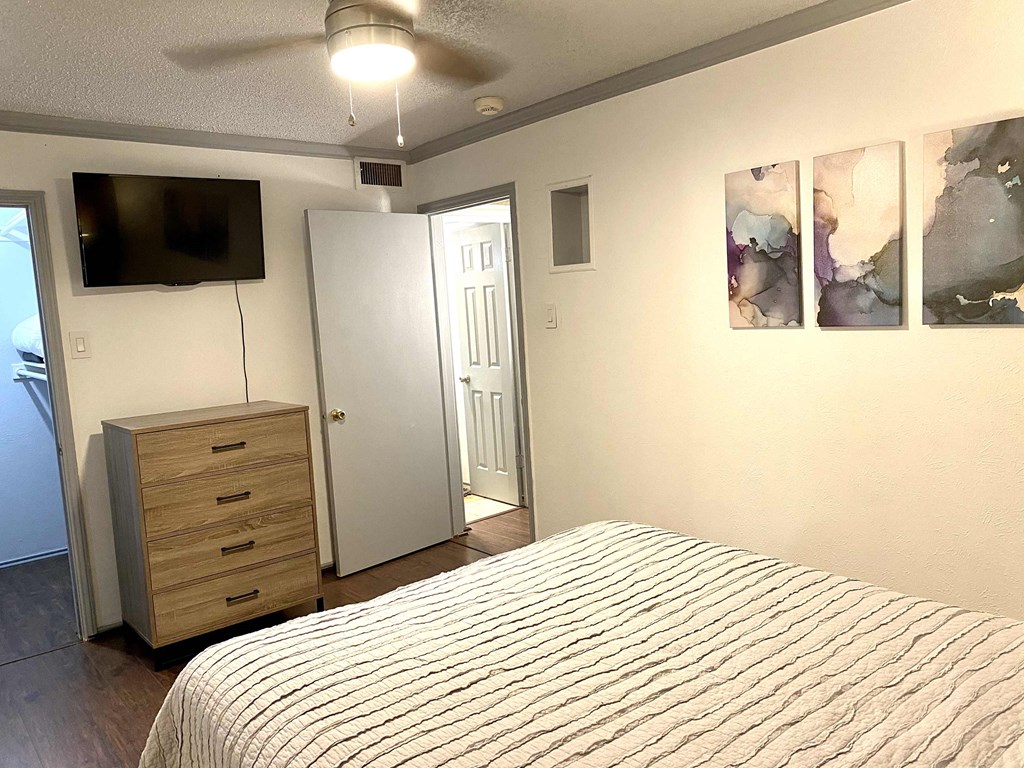 a bedroom with a bed and a dresser and a tv