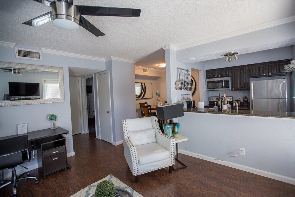 the view of a living room and kitchen with a desk and a chair