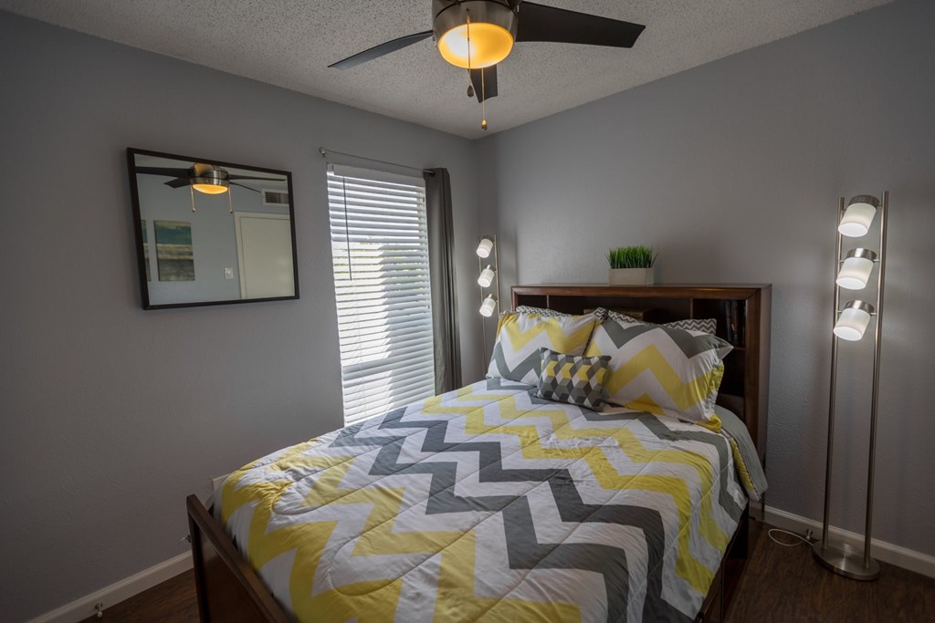 a bedroom with a yellow and gray bed and a ceiling fan
