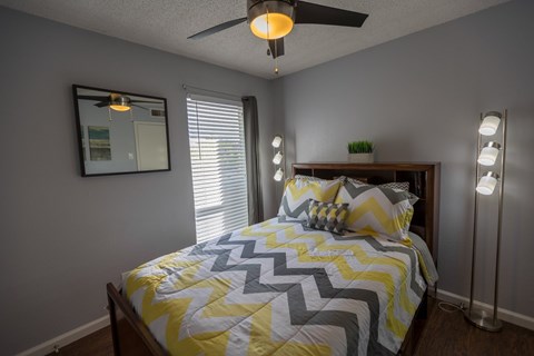 a bedroom with a yellow and gray bed and a ceiling fan