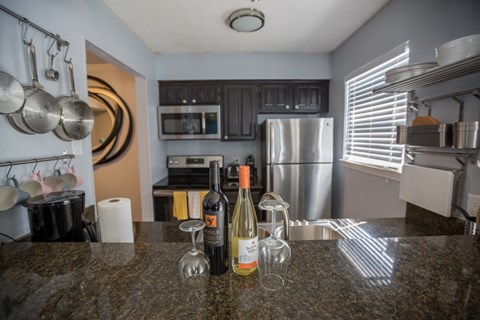 a kitchen with stainless steel appliances and a counter top with bottles of wine