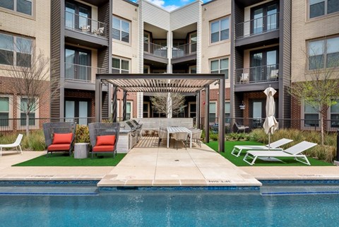 an outdoor patio with a pool and furniture in front of an apartment building