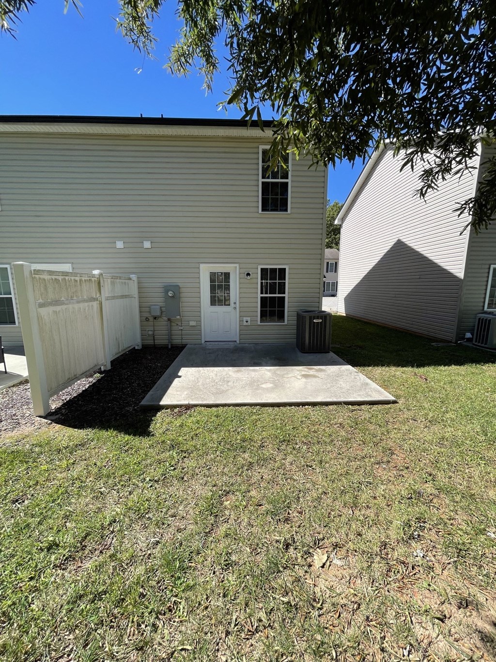 a white house with a white fence and a concrete driveway