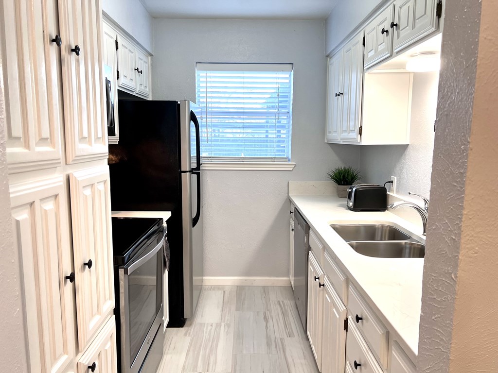 an empty kitchen with white cabinets and a black refrigerator