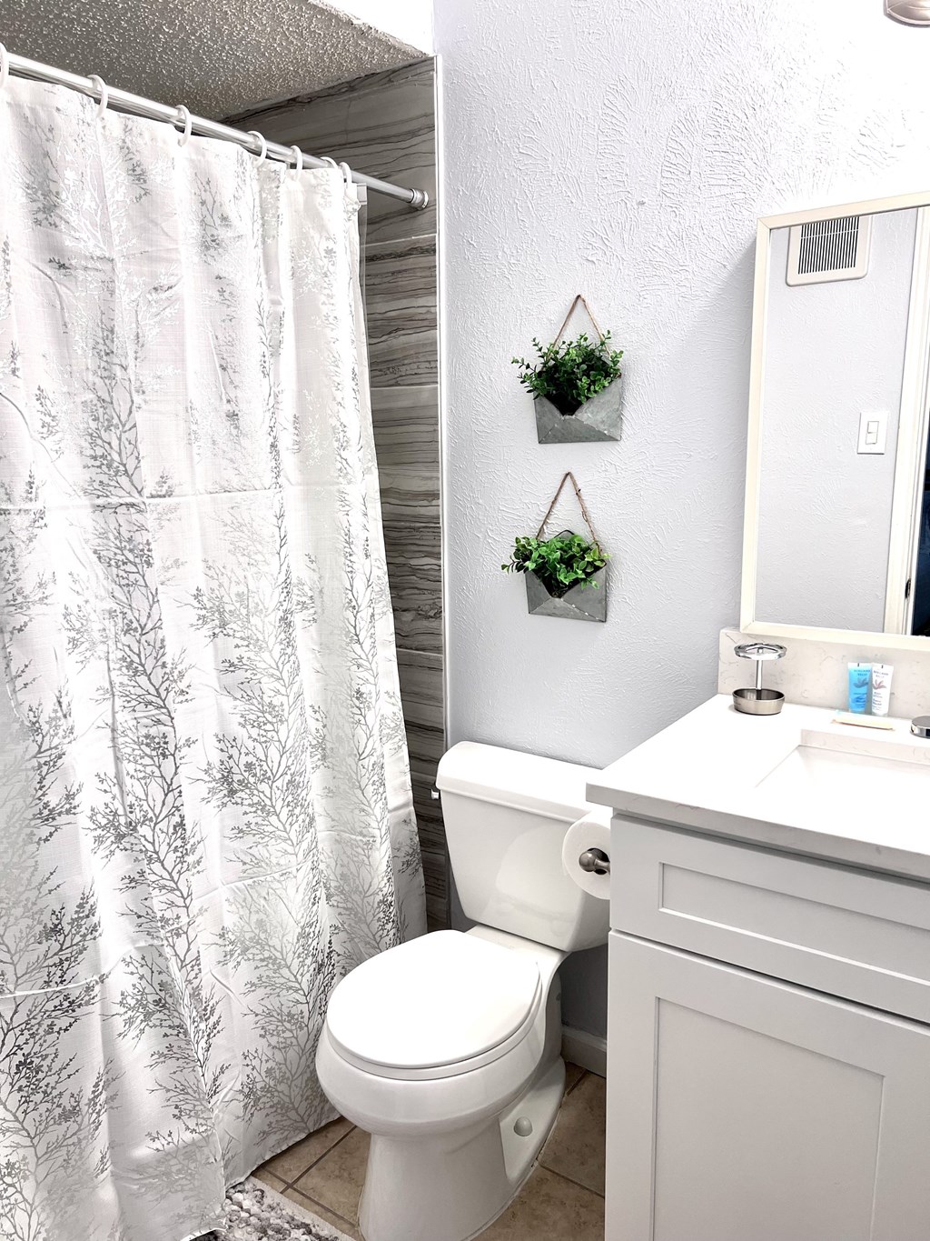 a bathroom with a white toilet and a shower curtain