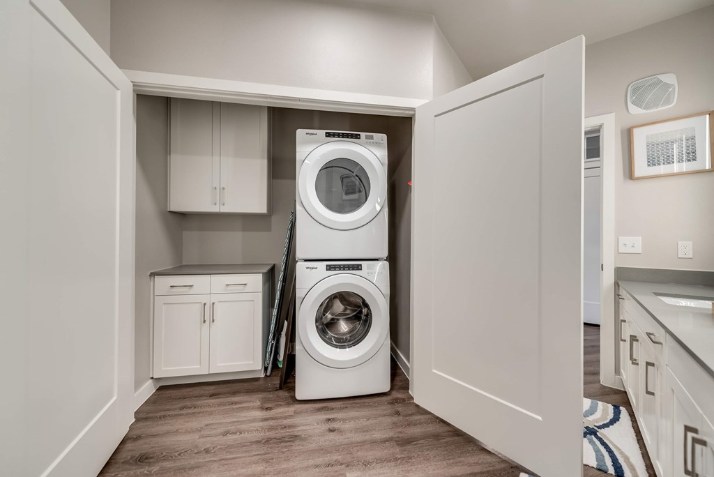 a white washer and dryer in a laundry room with white cabinets