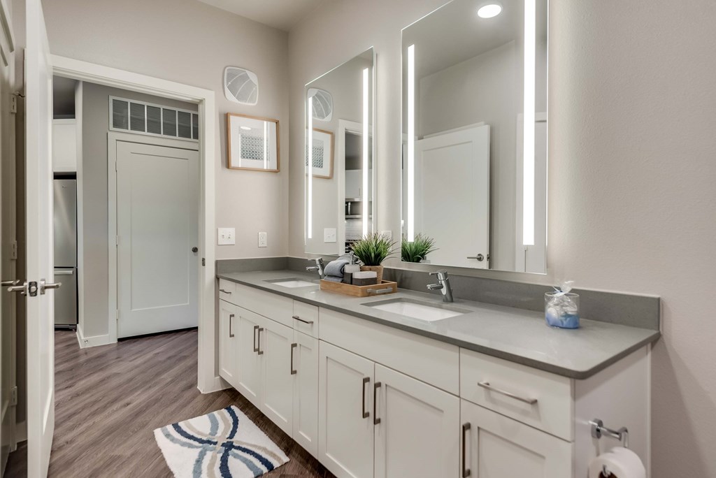 a bathroom with white cabinets and a sink and mirrors