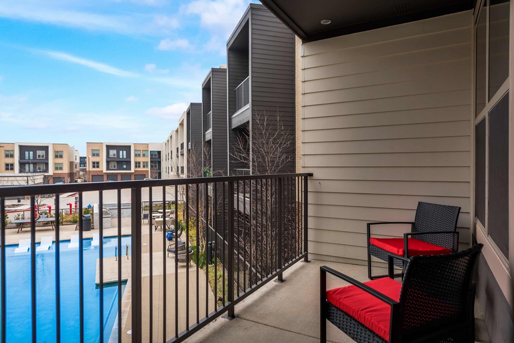 a balcony with a pool and chairs and a building in the background