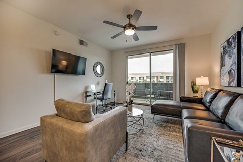 a living room with a large window and a ceiling fan