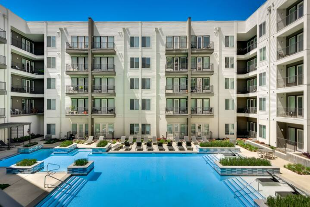 a large swimming pool in front of an apartment building