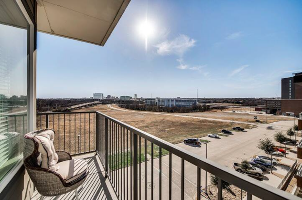 a balcony with a chair and a view of a parking lot