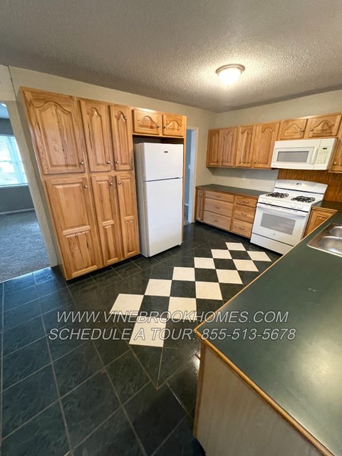 A kitchen with wooden cabinets and a checkered floor.