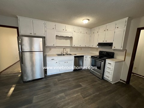 A kitchen with white cabinets and a stainless steel refrigerator.