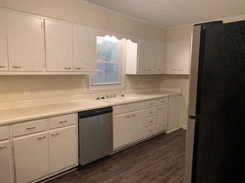 A kitchen with white cabinets and a black refrigerator.