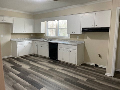 a kitchen with white cabinets and a wooden floor