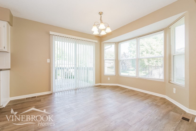 the living room of a home with a wood floor and large windows