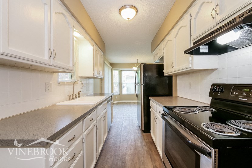 a kitchen with white cabinets and a black stove and refrigerator