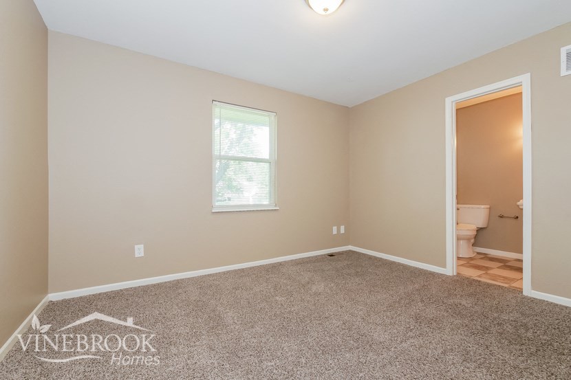 the bedroom of a home with carpet and a toilet