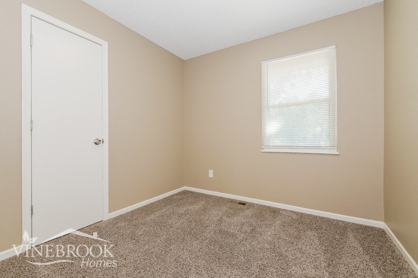 a bedroom with carpet and a door and a window