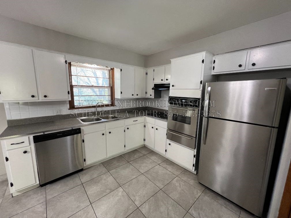 A kitchen with white cabinets and a stainless steel refrigerator.