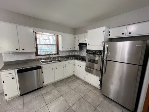 A kitchen with white cabinets and a stainless steel refrigerator.