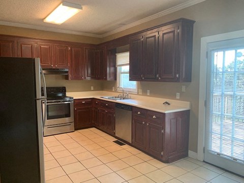 A kitchen with dark wood cabinets and a black refrigerator.