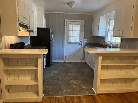 A kitchen with a black fridge and white cabinets.
