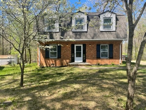 A small brick house with a white door and windows.