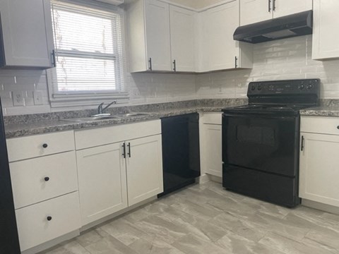 A black oven sits in a kitchen with white cabinets.