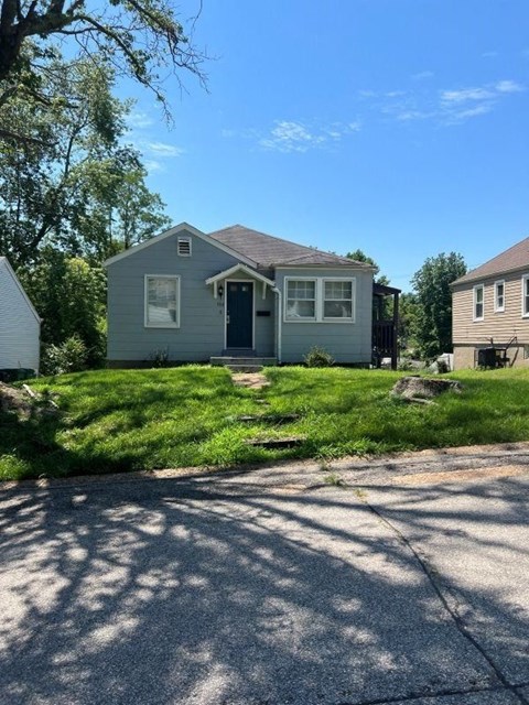 a blue house with a yard and a driveway